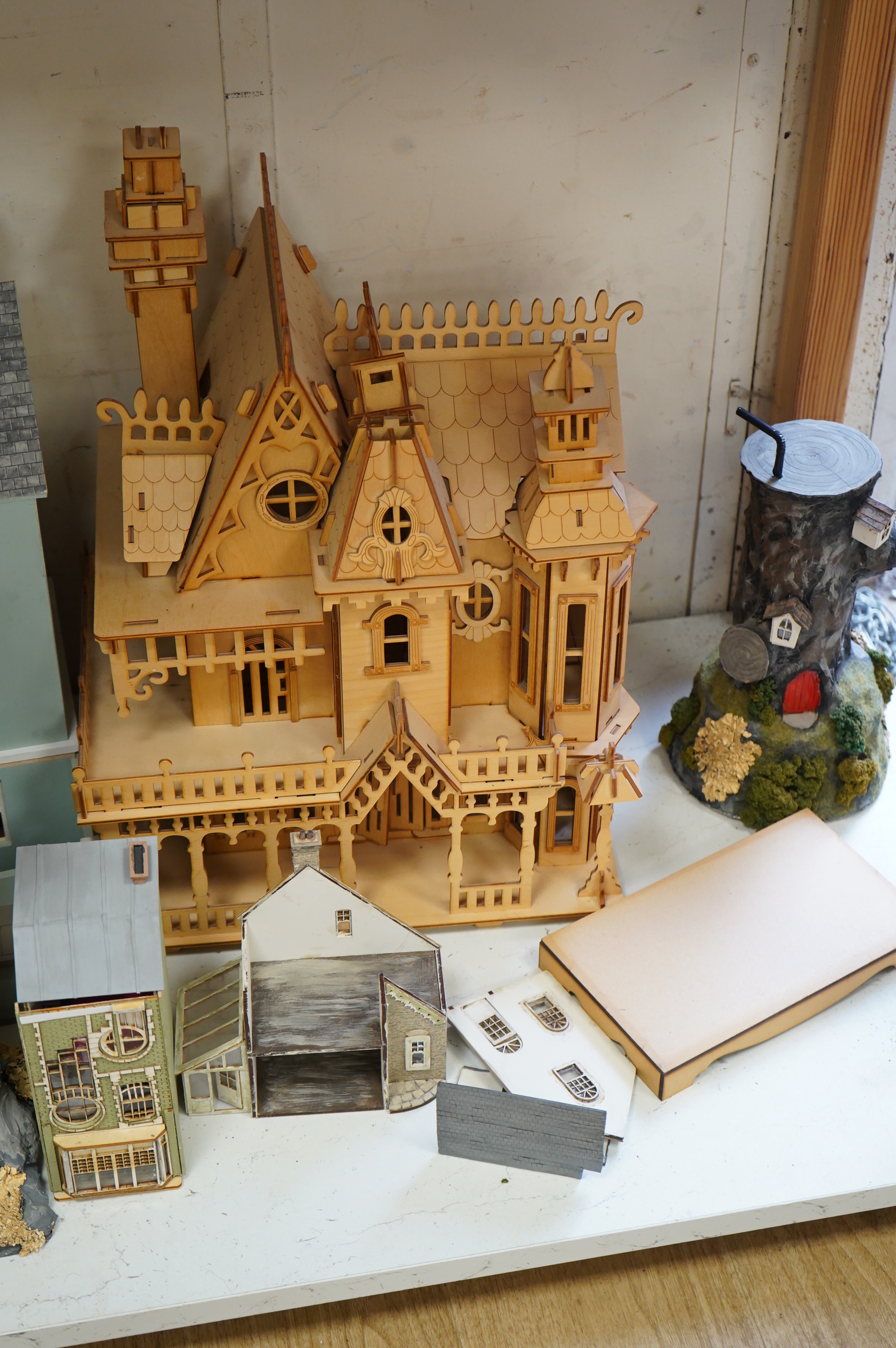 A modern plywood slot together model of a chateau, 50cm high, together with six miniature doll’s houses, a miniature wrought iron garden bench and chair set, and three miniature wooden chairs. Condition - fair.